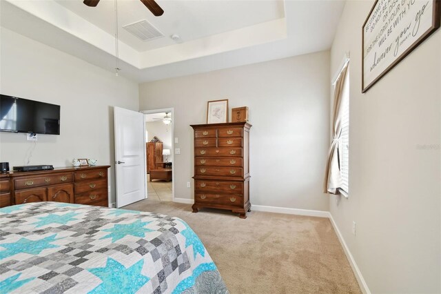 bedroom featuring ceiling fan, light colored carpet, and a raised ceiling