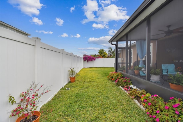 view of yard featuring ceiling fan and a sunroom