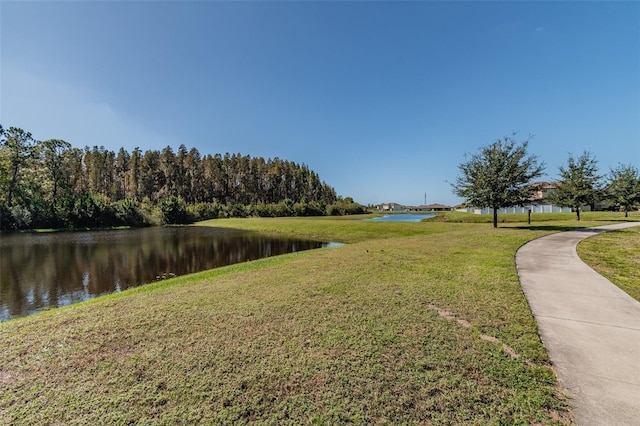 view of property's community with a water view and a lawn