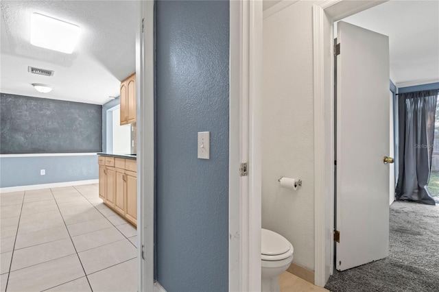 bathroom with toilet, tile patterned flooring, and a textured ceiling