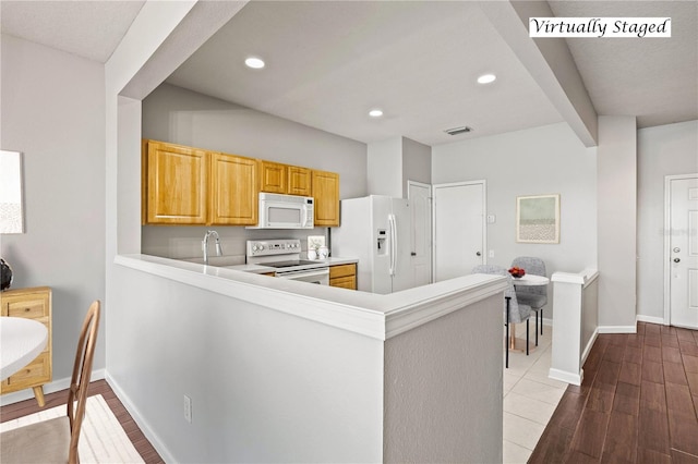 kitchen featuring hardwood / wood-style flooring, beam ceiling, white appliances, and kitchen peninsula