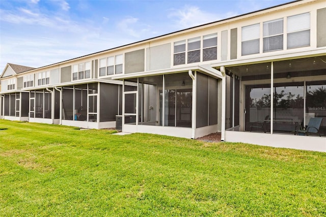 back of property with a yard and a sunroom