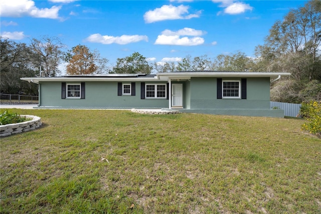 ranch-style home with a front yard and solar panels