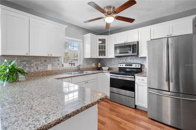 kitchen with light stone countertops, white cabinets, appliances with stainless steel finishes, and sink