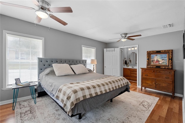 bedroom with ceiling fan, connected bathroom, and hardwood / wood-style floors