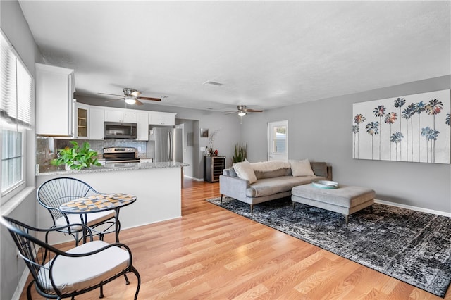 living room with ceiling fan and light wood-type flooring