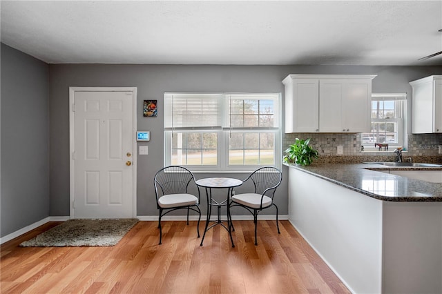 kitchen with kitchen peninsula, a healthy amount of sunlight, decorative backsplash, white cabinets, and sink