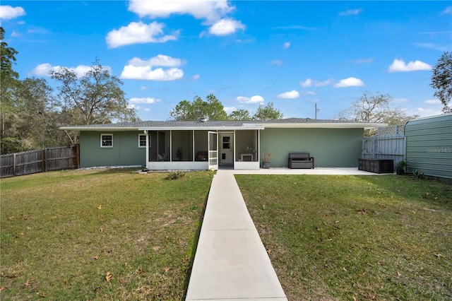 rear view of property featuring a patio area, a sunroom, and a yard