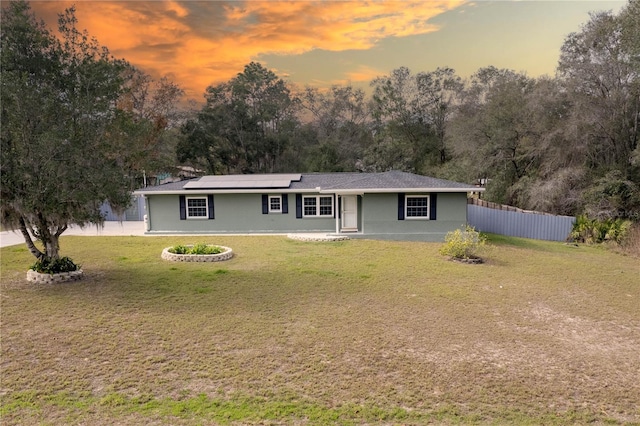 single story home with a lawn and solar panels