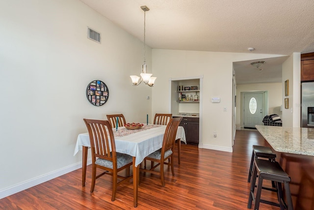 dining room featuring a textured ceiling, dark hardwood / wood-style floors, lofted ceiling, and a chandelier