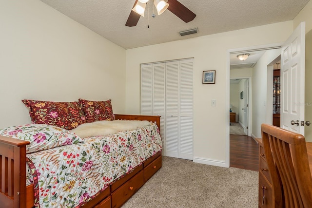 bedroom with ceiling fan, light colored carpet, a closet, and a textured ceiling