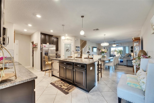 kitchen featuring sink, decorative light fixtures, a breakfast bar area, a kitchen island with sink, and appliances with stainless steel finishes