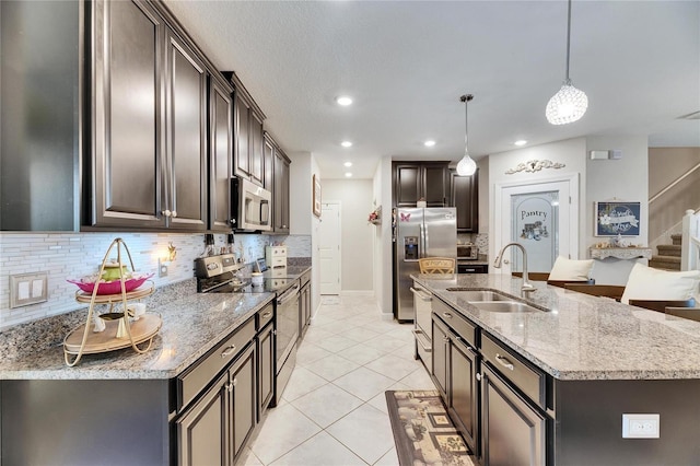 kitchen featuring sink, decorative light fixtures, dark brown cabinets, a center island with sink, and appliances with stainless steel finishes