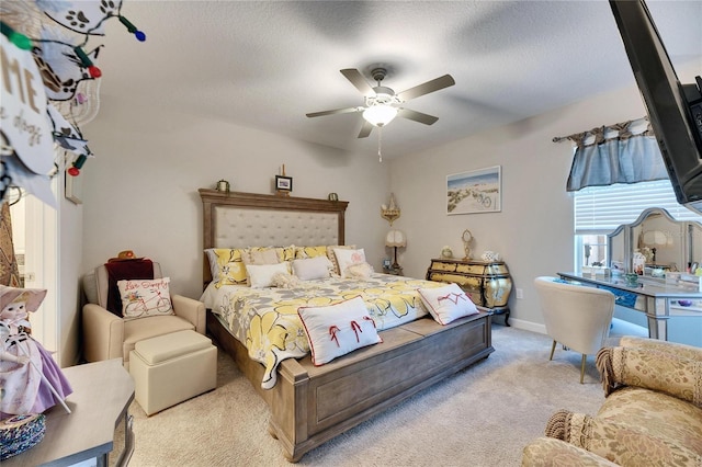 bedroom with ceiling fan, light colored carpet, and a textured ceiling