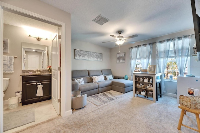 carpeted living room featuring ceiling fan, sink, and a textured ceiling