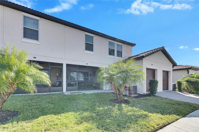 view of front of house with a garage, central AC, a sunroom, and a front lawn