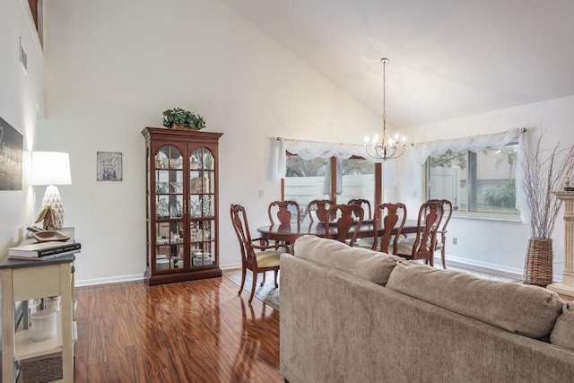 dining room featuring dark wood-type flooring, a notable chandelier, and high vaulted ceiling