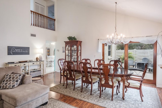 dining room with high vaulted ceiling, a notable chandelier, and hardwood / wood-style floors