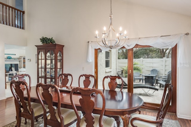 dining space with wood-type flooring, lofted ceiling, and a notable chandelier