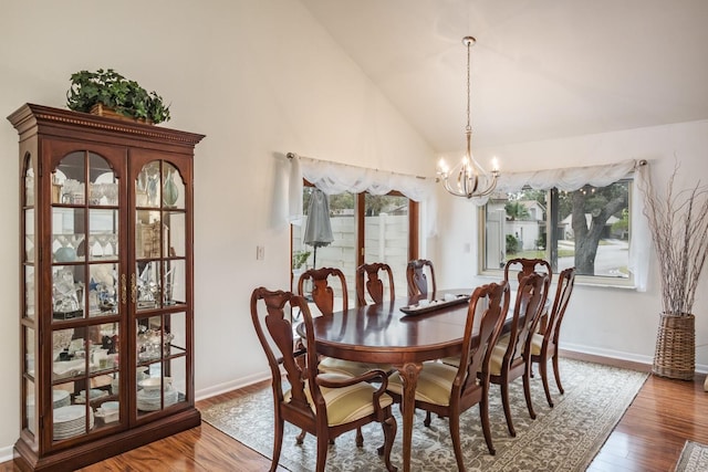 dining space with high vaulted ceiling, a notable chandelier, and hardwood / wood-style floors