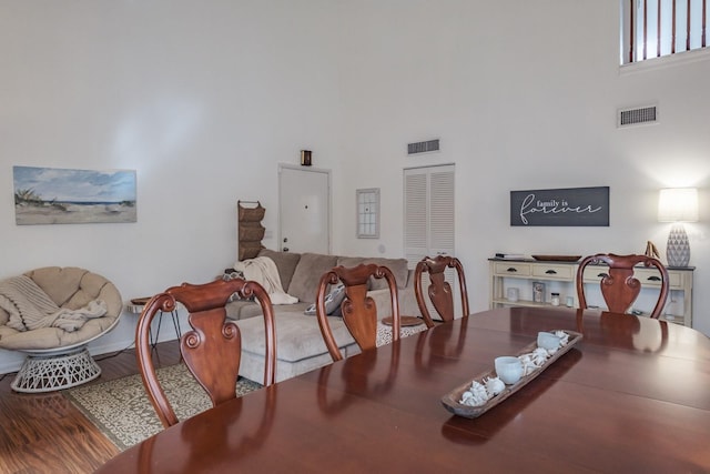 dining room with a towering ceiling and hardwood / wood-style flooring