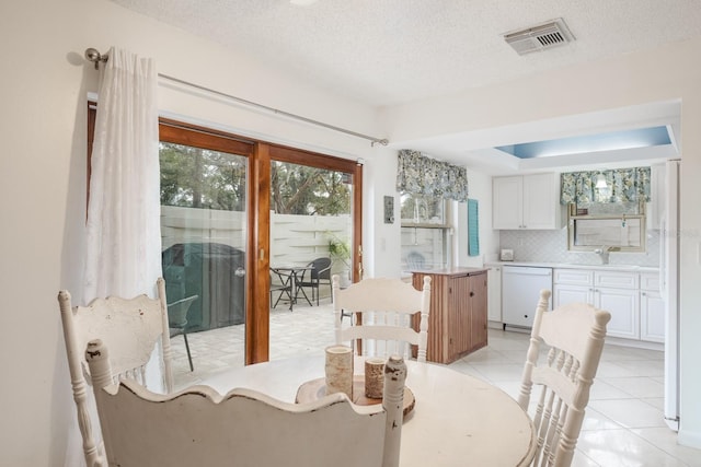 dining space featuring a textured ceiling, light tile patterned flooring, and sink