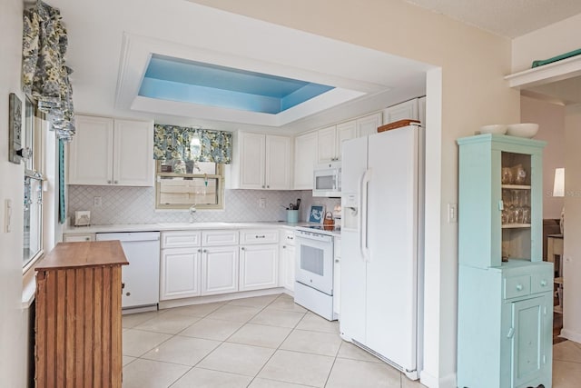 kitchen with light tile patterned floors, white cabinetry, a raised ceiling, white appliances, and sink