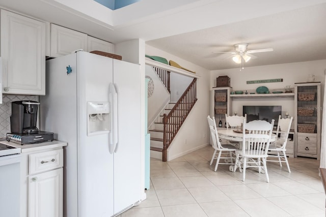 kitchen with light tile patterned flooring, ceiling fan, white cabinetry, and white fridge with ice dispenser