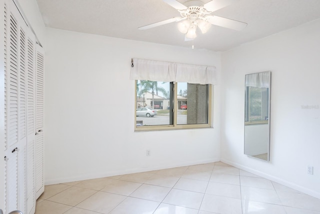 unfurnished bedroom featuring a textured ceiling, ceiling fan, light tile patterned floors, and a closet