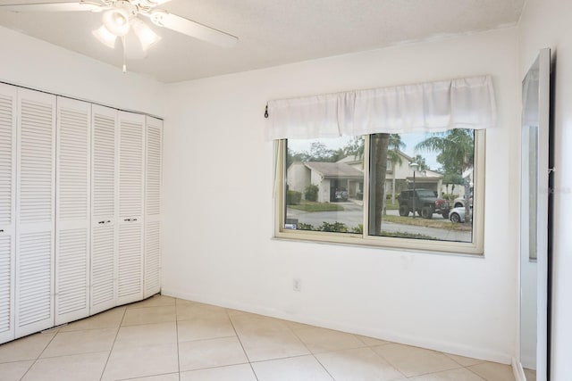 unfurnished bedroom with ceiling fan, light tile patterned floors, and a closet