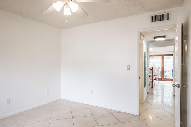 spare room with ceiling fan, light tile patterned floors, and a textured ceiling