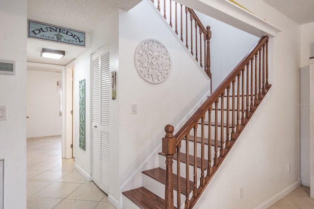 staircase featuring tile patterned floors and a textured ceiling