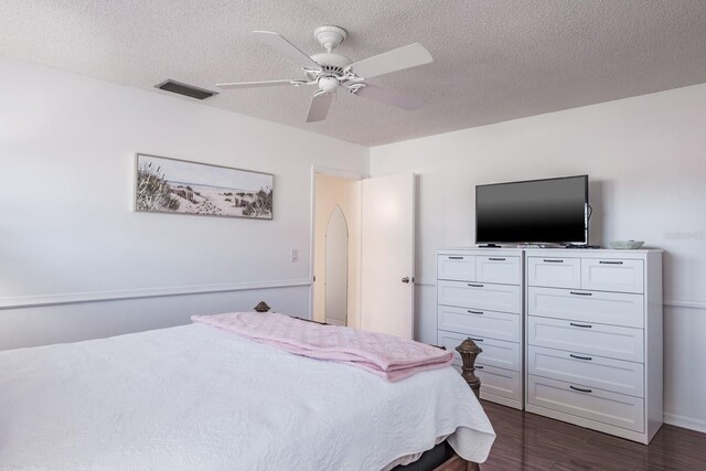 bedroom featuring ceiling fan, dark wood-type flooring, and a textured ceiling