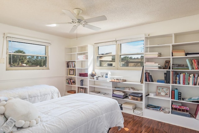 bedroom with ceiling fan, a textured ceiling, and dark hardwood / wood-style floors