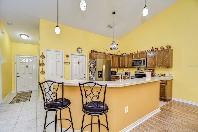 kitchen featuring decorative light fixtures, appliances with stainless steel finishes, and a kitchen island with sink