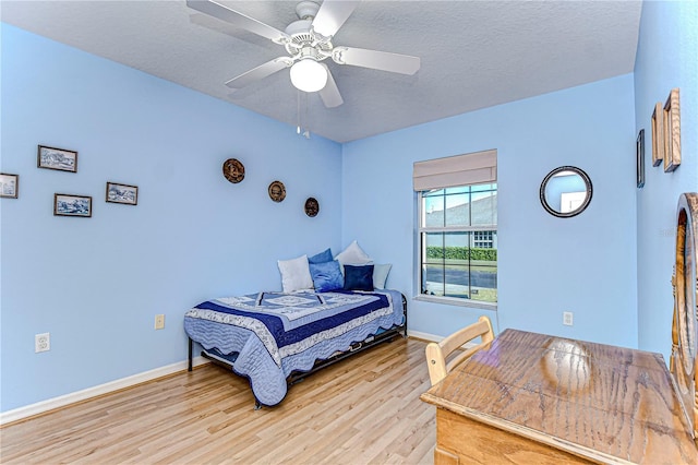 bedroom with a textured ceiling, ceiling fan, and light hardwood / wood-style flooring