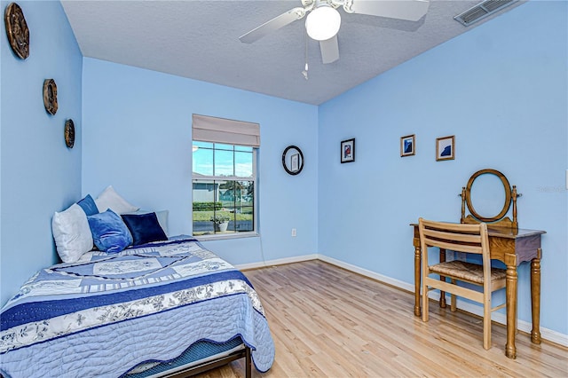 bedroom featuring a textured ceiling, ceiling fan, and light hardwood / wood-style floors