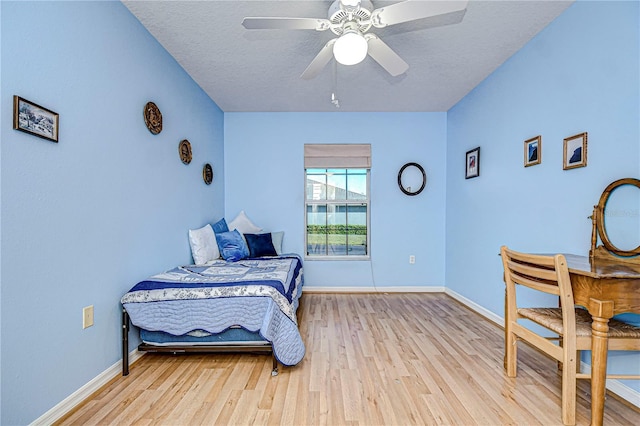 bedroom featuring ceiling fan, light wood-type flooring, and a textured ceiling