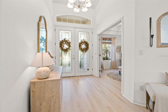 entryway featuring a healthy amount of sunlight, french doors, light wood-type flooring, and a notable chandelier