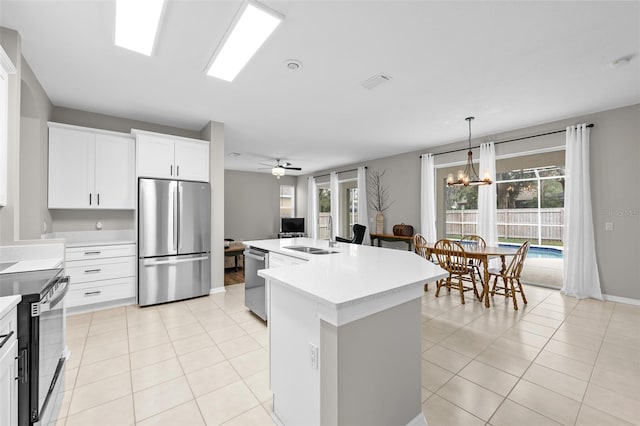 kitchen featuring ceiling fan with notable chandelier, white cabinetry, stainless steel appliances, an island with sink, and sink