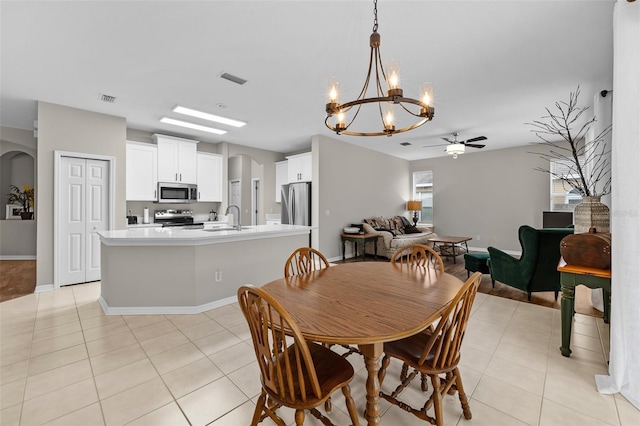 tiled dining space with ceiling fan with notable chandelier and sink