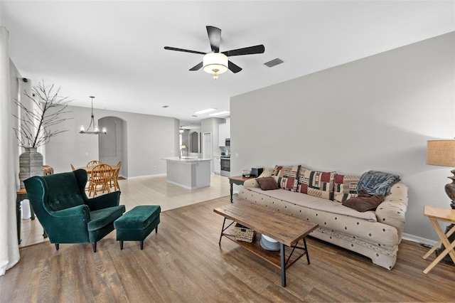 living room featuring light wood-type flooring and ceiling fan with notable chandelier