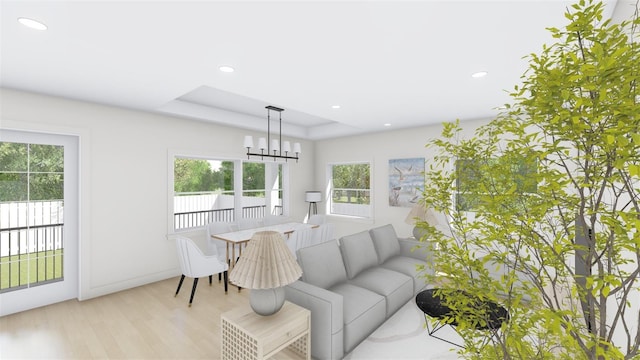 living room with light wood-type flooring, an inviting chandelier, and a tray ceiling