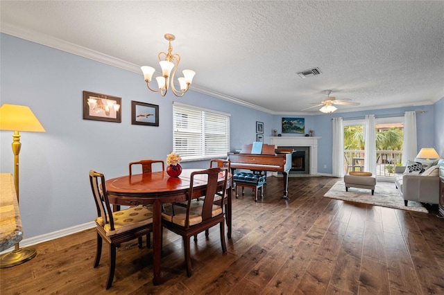 dining room with a textured ceiling, dark hardwood / wood-style flooring, crown molding, and ceiling fan with notable chandelier