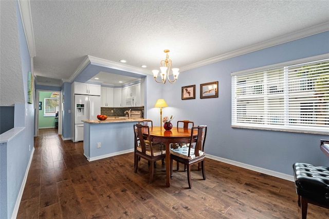 dining area with a textured ceiling, dark hardwood / wood-style flooring, ornamental molding, and a notable chandelier