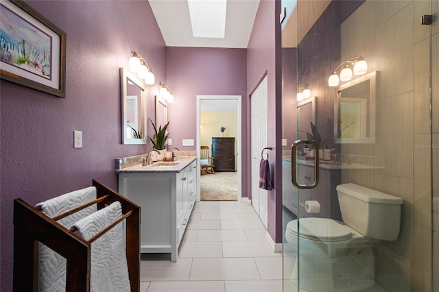 bathroom with tile patterned flooring, vanity, a skylight, toilet, and walk in shower