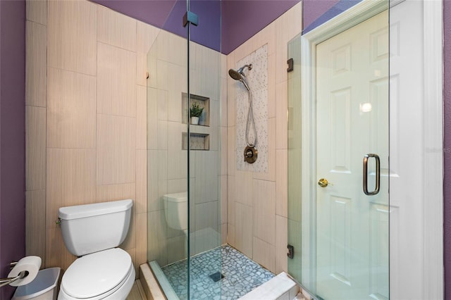 bathroom with a shower with shower door and toilet