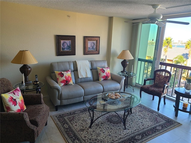 living room featuring ceiling fan, light tile patterned flooring, and a textured ceiling