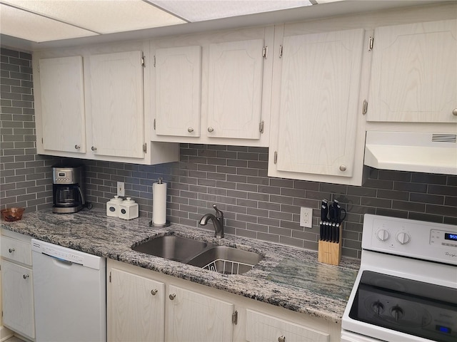 kitchen with decorative backsplash, sink, stone countertops, and white appliances