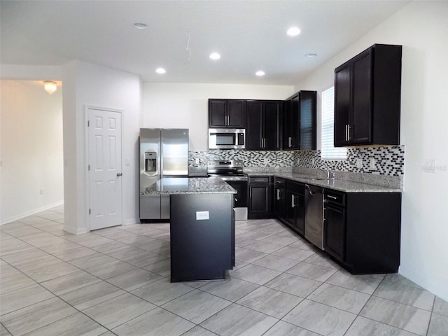 kitchen featuring a kitchen island, stainless steel appliances, sink, light tile patterned flooring, and light stone counters